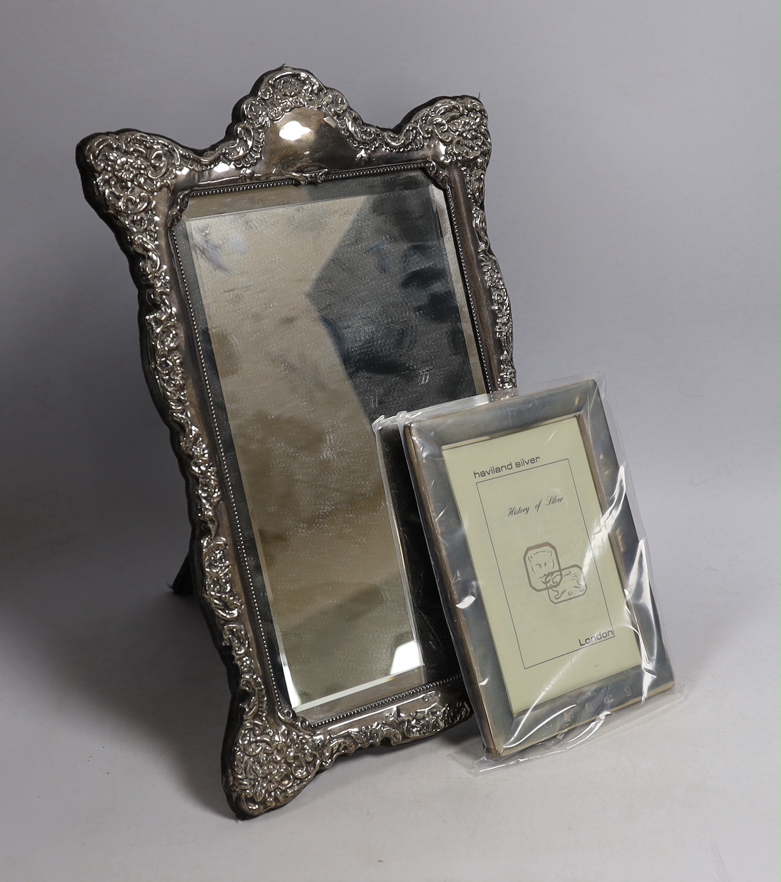 A modern Victorian style embossed silver easel framed mirror, 37cm and a smaller modern silver mounted photograph frame.